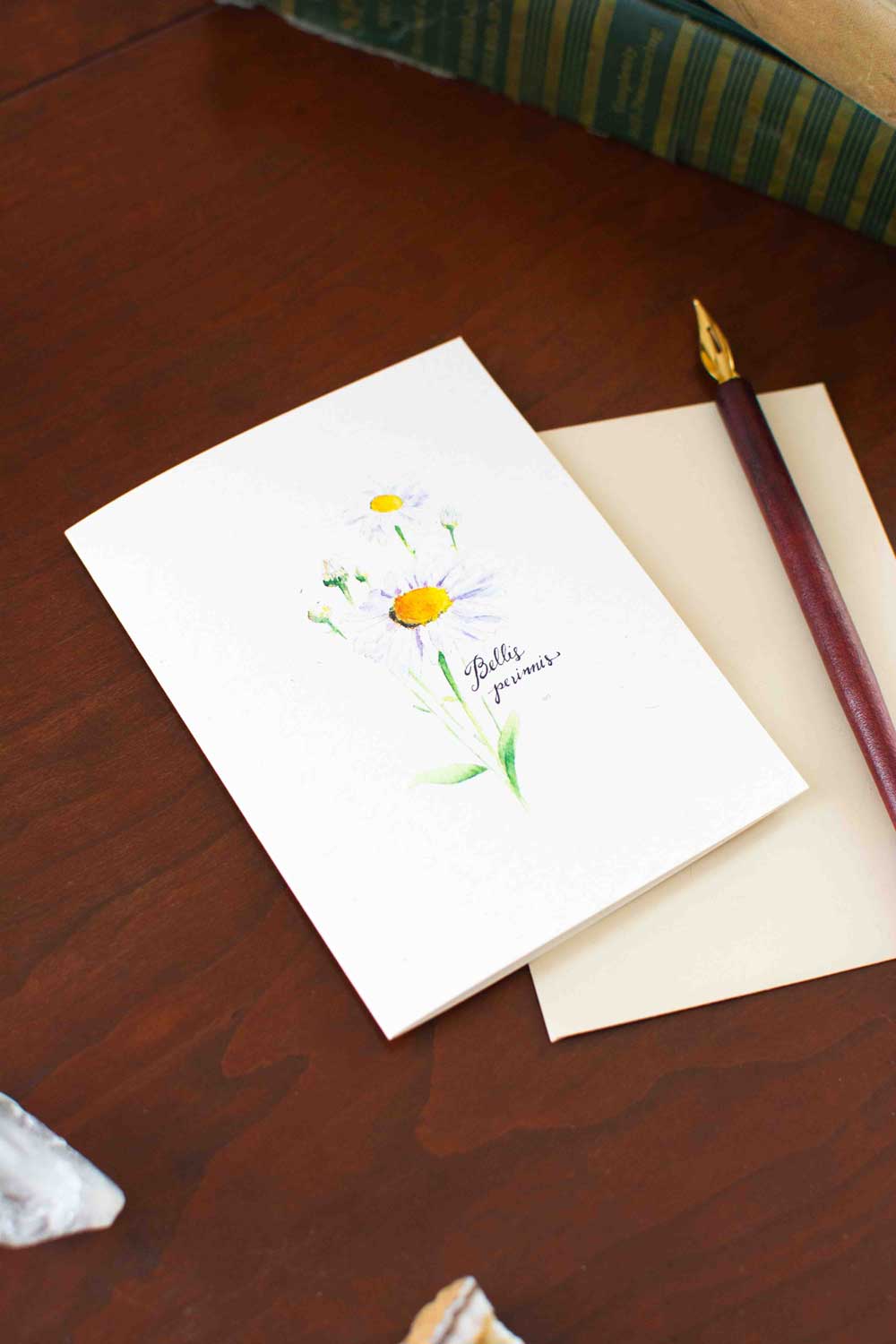 Greeting card with floral Daisy design and pen on wooden surface