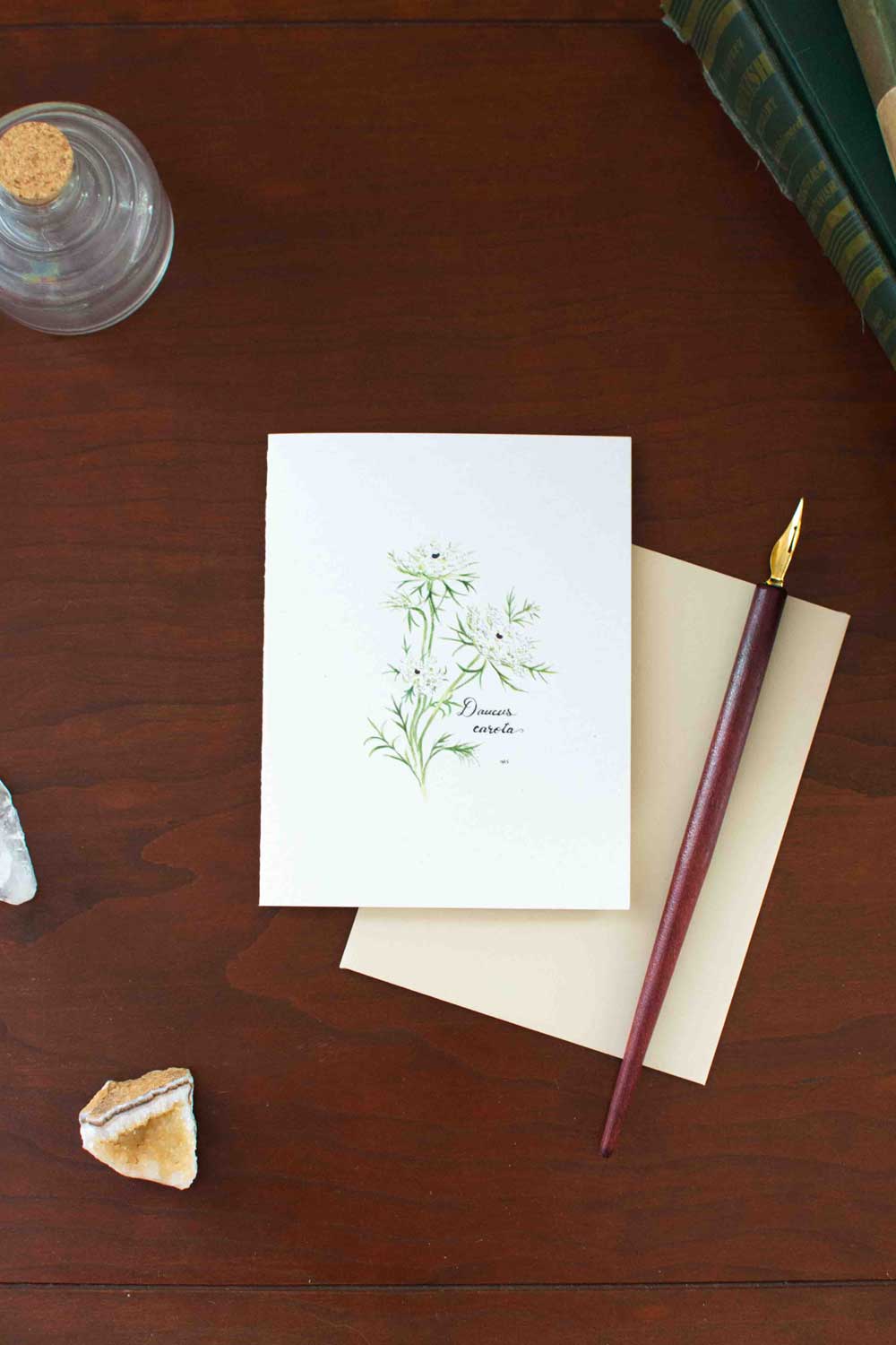 Greeting card with floral Queen Anne's Lace design and fountain pen on wooden surface