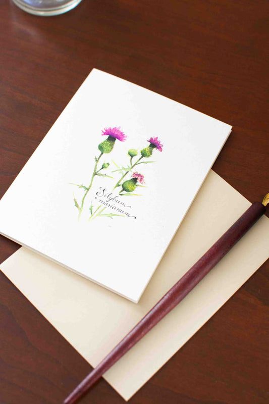 Notebook with floral Thistle design on cover and pen on wooden surface