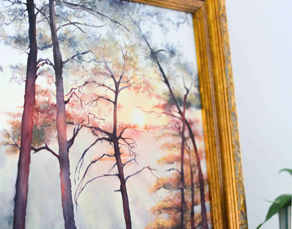 Corner of a painting of trees and a sunset at an overlook in a gold frame. 