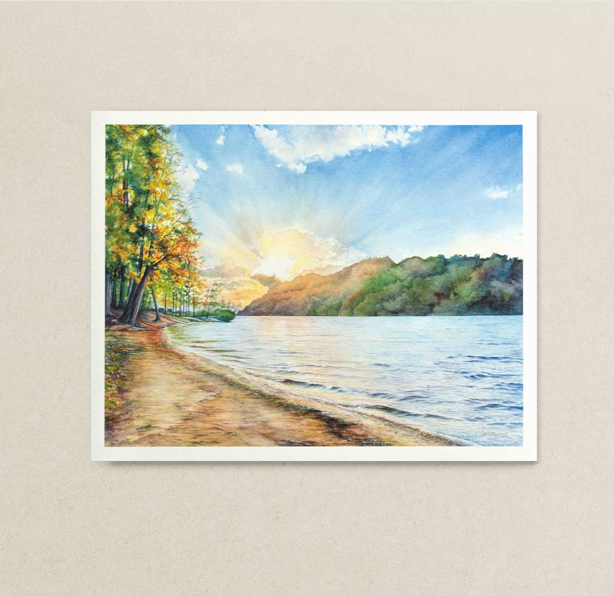 Art print of a watercolor landscape of Cheat Lake, WV with trees, water, and sky on a beige wall.