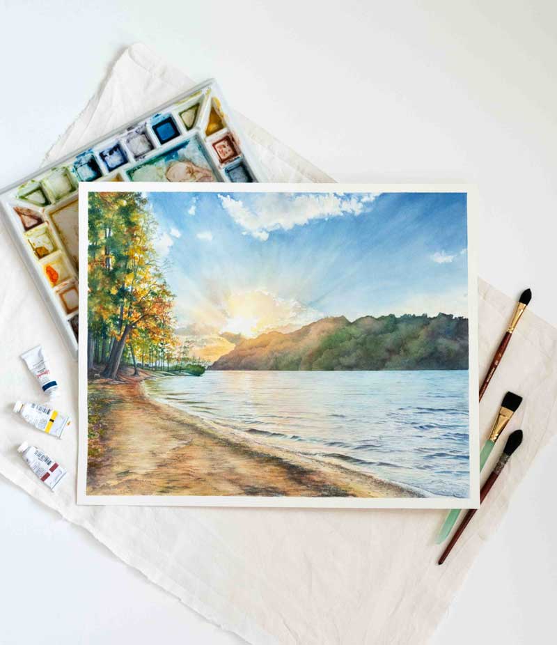 Painting of a scenic landscape of Cheat Lake surrounded by art supplies.