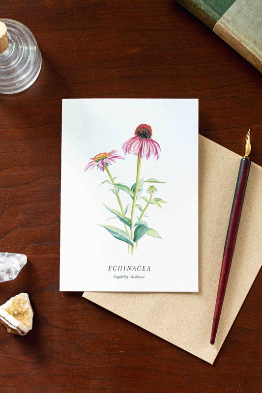 Note card with echinacea illustration on a wooden desk with pen and crystals