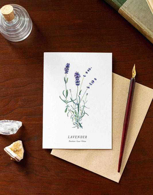 Note card with lavender illustration on a wooden desk with a pen and crystals.
