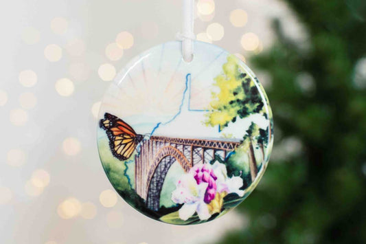 Ceramic ornament with a butterfly and rhododendron design and the WV state outline
